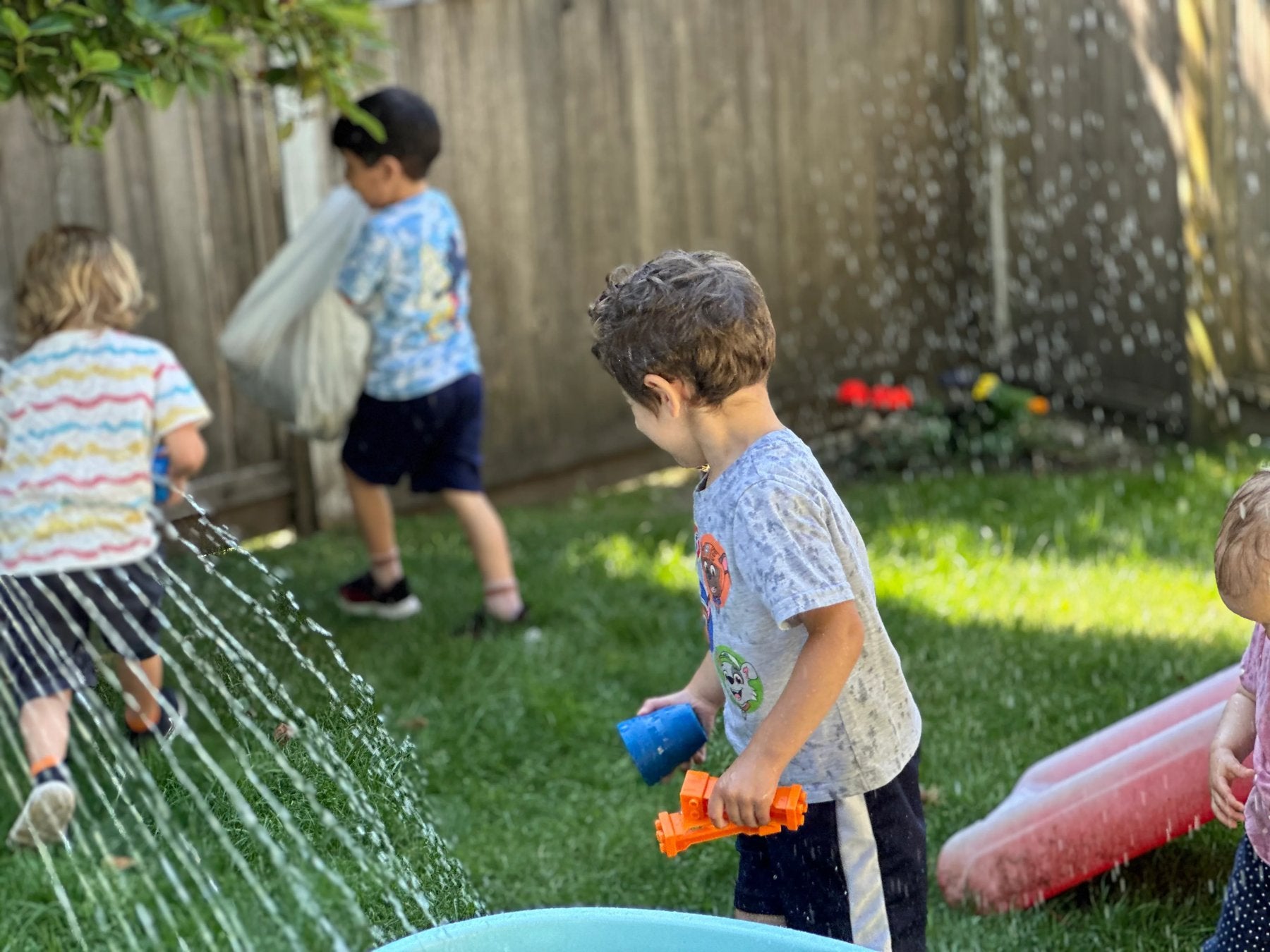 Children running and playing with water in the backyard